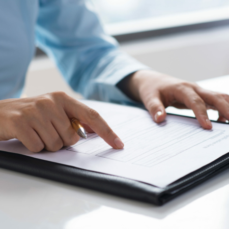 Closeup of person reading and studying document. Entrepreneur sitting at desk. Paperwork concept. Cropped view.