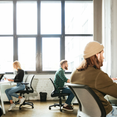 Picture of young colleagues work in office using computers. Looking aside.